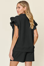 Back view of model styled in black Facts Only Fit Set with flowing cap sleeves and drawstring shorts.