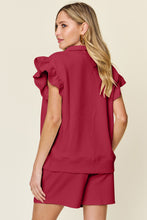 Back view of model styled in deep red Facts Only Fit Set with flowing cap sleeves and drawstring shorts.