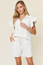 Model walking in white Facts Only Fit Set, paired with heels for a casual-chic look.