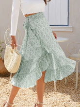 Side pose of model in Faylora Drift Skirt green, showcasing flowing ruffled hem and botanical floral print in motion