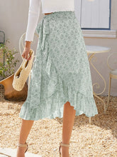 Faylora Drift Skirt front view in green botanical print with side tie waist and asymmetric ruffled hem