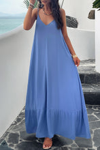 a model posing on a balcony wearing a sky blue Backless Maxi Cami Dress with Pockets  paired with jewelry, and clear heels