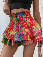 Side angle of red Floryza shorts showing draped floral ruffles.