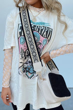 Model wearing the beige ChicGrid checkered mock neck blouse paired with distressed jeans, layered tee, long wide straped purse, and
jewelry, styled for a chic casual look.