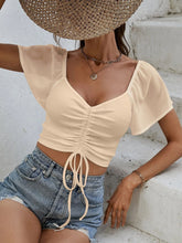 Close-up of adjustable front-center drawstring on Glowflutter Crop Top in tan, highlighting stretch fabric and ruching.