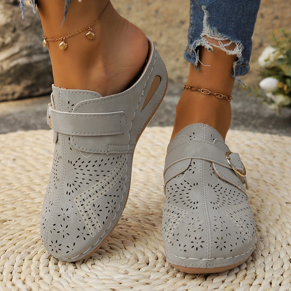 Model showcasing the front a pair of grey Suede Round Toe Wedge Sandals with two golden anklets and ripped blue jeans highlighting perforation detail.