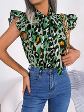 Side angle of green leopard print tie-neck blouse highlighting cap sleeve silhouette and lightweight, flowing material.