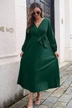 Model wearing Green Zeleviane Pleated Maxi Dress, highlighting surplice neckline, tie waist, and pleated skirt design.