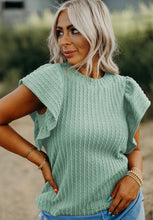Model styled in a gum leaf RuffleRidge Top with light blue jeans, sneakers, and accessories for a casual look.