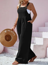 Close-up showing the square neckline and button accents on black Harmonique overalls.