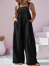 Model in black overalls at a rooftop gathering, styled with statement sunglasses and a bold clutch.