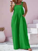 Plus size model wearing green Harmonique wide-leg overalls, front view styled with a white crop top, jewelry, a straw hat, and sandals.