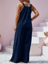 Rear shot of navy overalls showing full-length adjustable straps and relaxed leg cut.