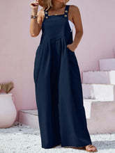 Close-up highlighting navy overalls’ center pocket and button-strap detailing.