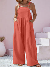 Plus size model in vibrant orange Harmonique overalls paired with a white tank and sneakers.