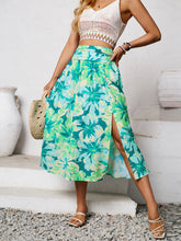 Model hand on hip posing in Havélyra Bloom Skirt multicolor styled with straw handbag and heels