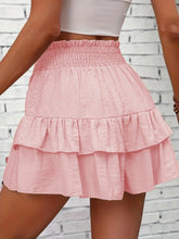 Pink ruffled skirt worn by a person near a white brick wall.