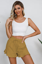 Model in honey shorts styled for a summer farmers’ market visit with sandals and a woven bag.
