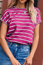 Woman wearing hot pink striped knit short sleeve top at a weekend party, styled with shorts, sneakers, and a crossbody bag.