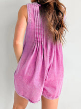 Hot pink romper from behind, highlighting pleated back design and curve-enhancing fit, styled with a high ponytail and statement earrings.