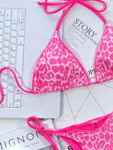 Close-up flat lay detail of hot pink leopard print tie side bikini set showing halter neck and side tie string details