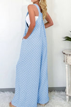 Model showing back view of checkered overalls with v-neckline and adjustable wide straps.