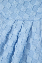 Macro shot of light blue checkered fabric texture showing softness and weave detail.
