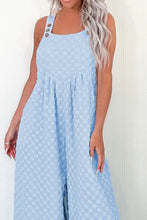 Close-up of model wearing checkered overalls highlighting front pocket and button strap detail.