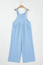 Light blue checkered wide-leg overalls front view hanging on wooden hanger.