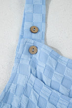 Detailed flatlay of wide strap with button fastening on checkered textured fabric.