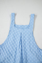 Close-up of back v-neckline and strap buttons on checkered overalls.