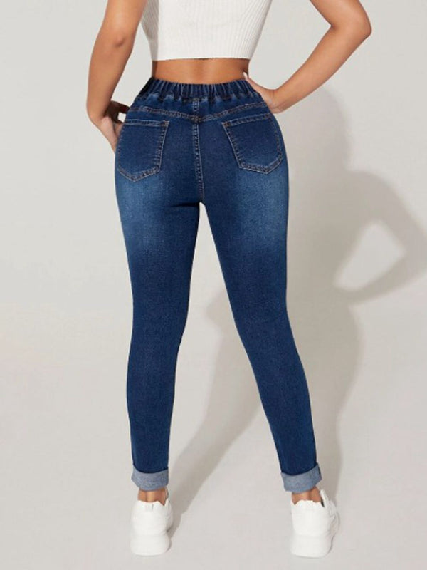 A female model posing from the back wearing the Kavoya DriftFlex Elastic Waistband & Drawstring Cropped Denim Pants paired with a  white blouse and white sneakers.