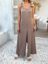 Model styled with layered necklaces and strappy sandals in taupe jumpsuit.