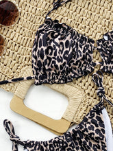 Close-up flat lay detail of leopard frill trim halter neck bikini set showing adjustable tie strings and frill trim detail