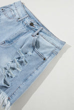 Close-up of distressed detail and raw hem on light blue high waist denim shorts, showcasing soft washed denim texture.