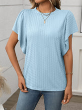 Model in a light blue Round Neck Flutter Sleeve T-Shirt, styled with wide-leg linen pants and a straw tote at a sunny garden brunch.