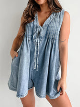 Model seated outdoors on wooden steps, light blue romper flowing naturally—sunlit denim highlighting soft texture and comfort.