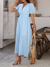 Model in light blue Velunira dress strolling through a garden brunch party.