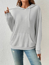 Front view of a woman in the Calvessa Hoodie in light gray, showcasing the casual silhouette, relaxed sleeves, and adjustable drawstring hood.