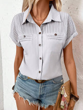 Side profile of model in a light gray pleated collared neck blouse with cuffed sleeves, styled with gold hoop earrings and neutral sandals.
