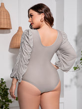 Back view of plus-size model in light gray Confidently Me one-piece swimsuit showing U-back design and ruched balloon sleeves