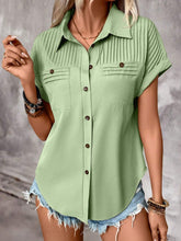 Model wearing a light green pleated collared neck short sleeve blouse with button-up front, paired with light denim jeans, styled for a casual day out.
