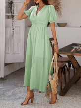 Model in light green Velunira dress with V-neckline and puff sleeves.