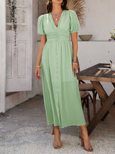 Model in light green Velunira dress walking through a serene countryside estate.