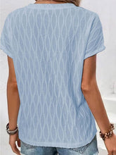 A woman showcasing the back of a light blue Full Size Ruched Wavy Textured Round Neck Short Sleeve T-Shirt riding the subway in New York City.
