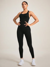 ont view of woman wearing black LuminaCross Apex Jumpsuit, sleeveless silhouette.