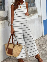 Model wearing a Lunalvia Striped Round Neck Wide Leg Jumpsuit while strolling along a sunny beach resort pathway, paired with strappy sandals, sunglasses, and a woven straw tote, capturing an effortless, breezy vacation look.