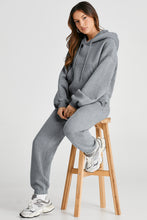 Model sitting casually on bar stool in gray Lunetta DriftSet, sleeves rolled up.