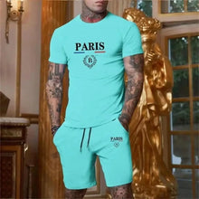 Man in turquoise Luvéris Paris Crest Set with hands in pockets at in an elegant interior setting.