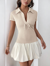 Model wearing the Luxessity Johnny Collar Mini Dress in Tan, featuring a deep V-neck, Johnny collar, ruched waist, and front bow tie.